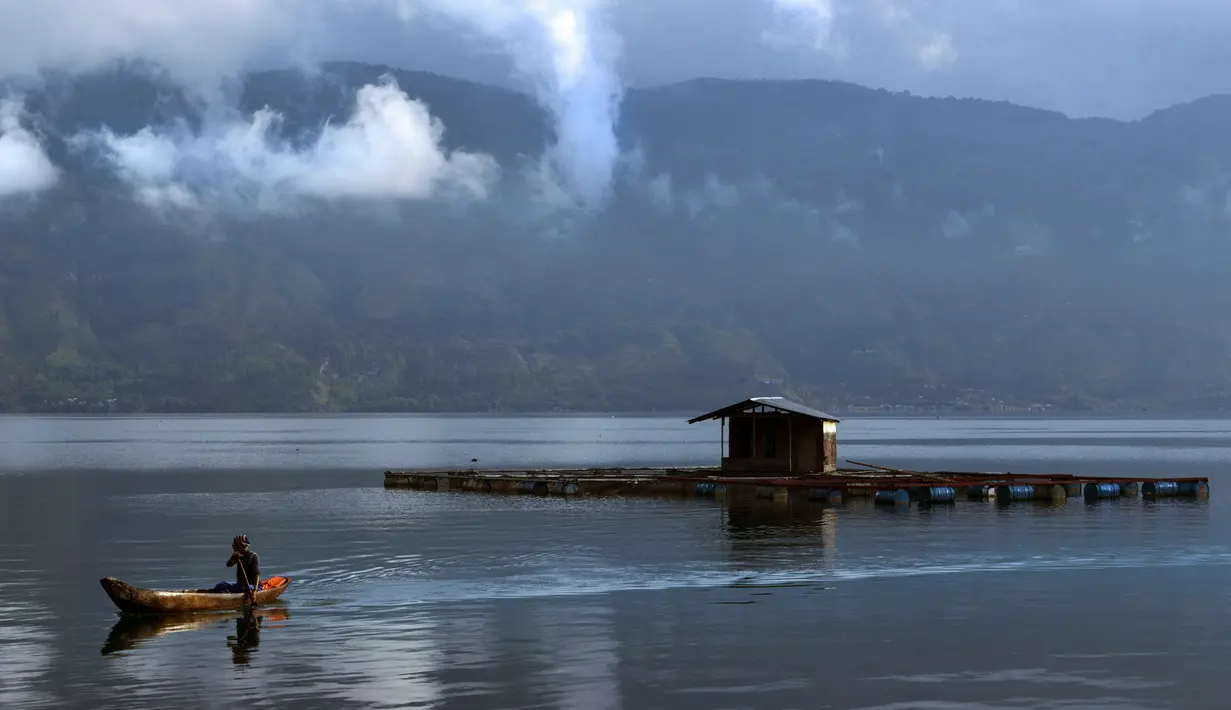 Seorang lelaki mengayuh perahu dayung di danau Laut Tawar di Takengon, provinsi Aceh tengah, (1/3). Danau Laut Tawar adalah sebuah danau dan kawasan wisata yang terletak di Dataran Tinggi Gayo, Kabupaten Aceh Tengah, Aceh. (AFP Photo/Chaideer Mahyuddin)