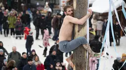 Seorang pria berusaha memanjat di sebuah tiang saat perayaan liburan Maslenitsa (Shrovetide) di Moskow, Rusia (18/2). Liburan ini menandai berakhirnya musim dingin yang dirayakan sejak masa pagan. (AP Photo / Pavel Golovkin)