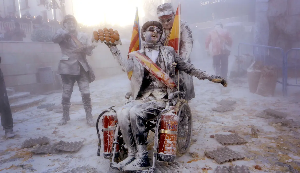 Peserta berkursi roda membawa telur saat mengikuti festival Els Enfarinats di Kota Ibi, Spanyol, Sabtu (28/12/2019). Dalam festival yang sudah berlangsung selama 200 tahun ini para peserta bertempur menggunakan tepung, telur, dan petasan. (AP Photo/Alberto Saiz)