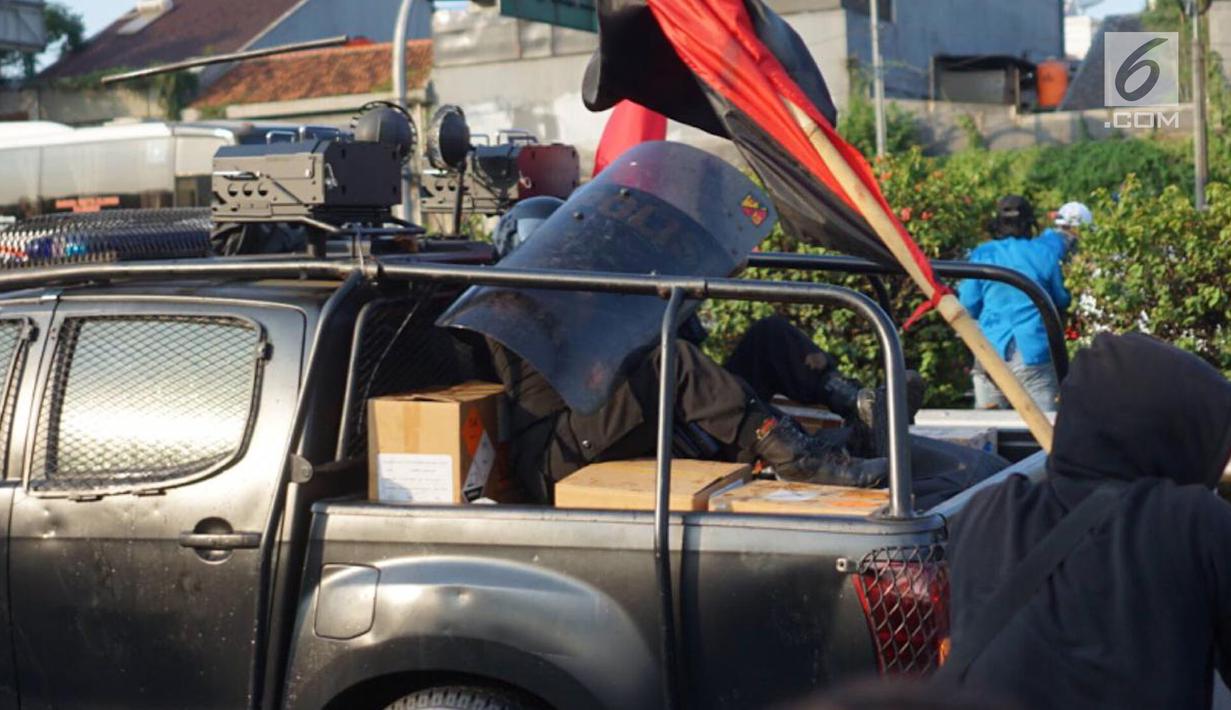Seorang polisi berlindung di balik tameng saat kendaraan yang dinaiki diserang massa pelajar dalam unjuk rasa di sekitar kawasan DPR RI, Jakarta, Senin (30/9/2019). Sempat terjadi kericuhan akibat peristiwa tersebut hingga menyebabkan jalan tol ditutup. (Liputan6.com/Immanuel Antonius)