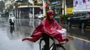 Pejalan kaki yang mengenakan jas hujan mengendarai sepeda saat hujan deras di Hanoi (14/10/2020). Badai tropis Nangka menghantam Vietnam tengah-utara yang mengakibatkan bencana alam, terutama hujan lebat dan banjir, telah menyebabkan 28 orang tewas dan 12 lainnya hilang. (AFP Photo/Manan Vatsyayana)