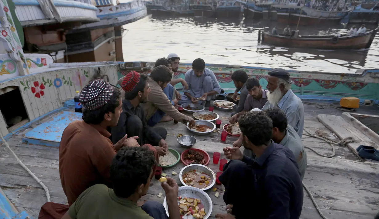 Nelayan berbuka puasa selama bulan suci Ramadhan, di galangan kapal, di Karachi, Pakistan, Selasa (20/4/2021). (AP Photo / Fareed Khan)