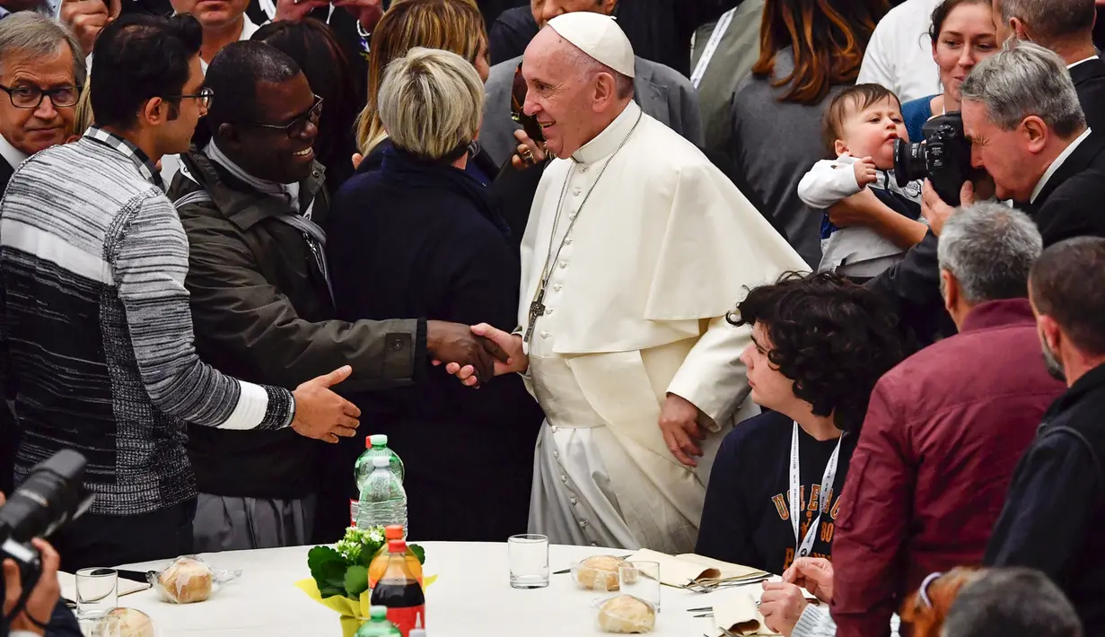 Paus Fransiskus tiba untuk menghadiri makan siang bersama sejumlah orang miskin di Pope Paul VI, Vatikan, Minggu (18/11). Makan siang bersama ratusan kaum papa, tunawisma, dan pengangguran itu memperingati Hari Orang Miskin Sedunia. (Vincenzo PINTO/AFP)
