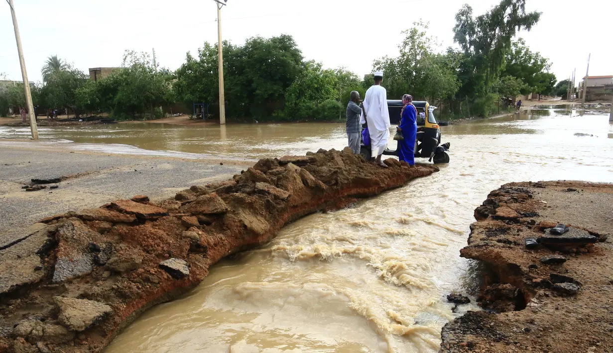 Sejumlah warga berdiri di dekat jalan yang tergenang banjir di Khartoum, Sudan (3/8/2020). Sudan dilanda banjir baru-baru ini akibat hujan lebat. (Xinhua/Mohamed Khidir)