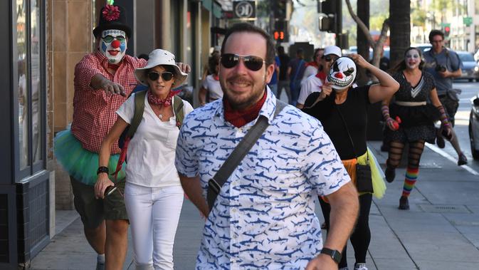 Peserta berdandan seperti badut mengejar pejalan kaki selama 'Running of the Clowns' di Pasadena, California pada 21 Oktober 2018. Lari dikejar kawanan badut ini merupakan parodi yang mengolok-olok lomba dikejar banteng di Spanyol. (Mark RALSTON/AFP)