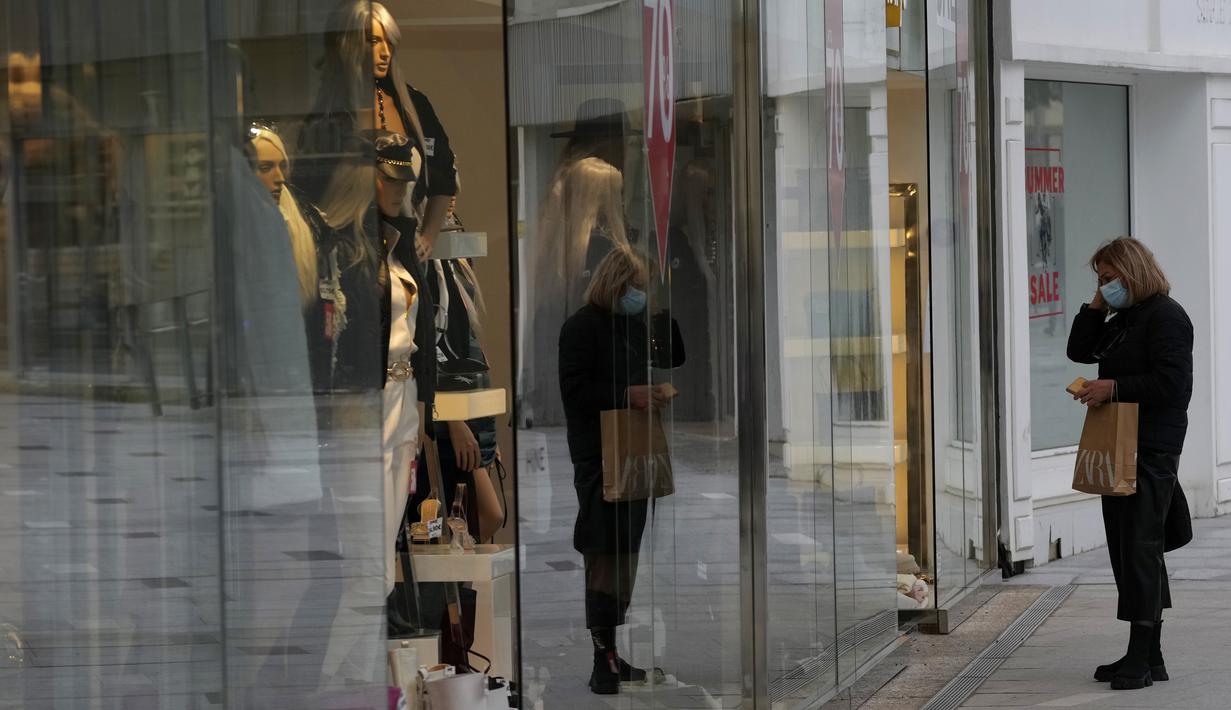 Seorang wanita terlihat di luar toko di sebuah jalan perbelanjaan utama di ibu kota pusat Nicosia, Rabu (19/1/2022). Mulai 1 Maret, Siprus akan mencabut persyaratan bagi pelancong menunjukkan hasil tes negatif COVID 19 selama memiliki sertifikat vaksinasi yang valid. (AP Photo/Petros Karadjias)