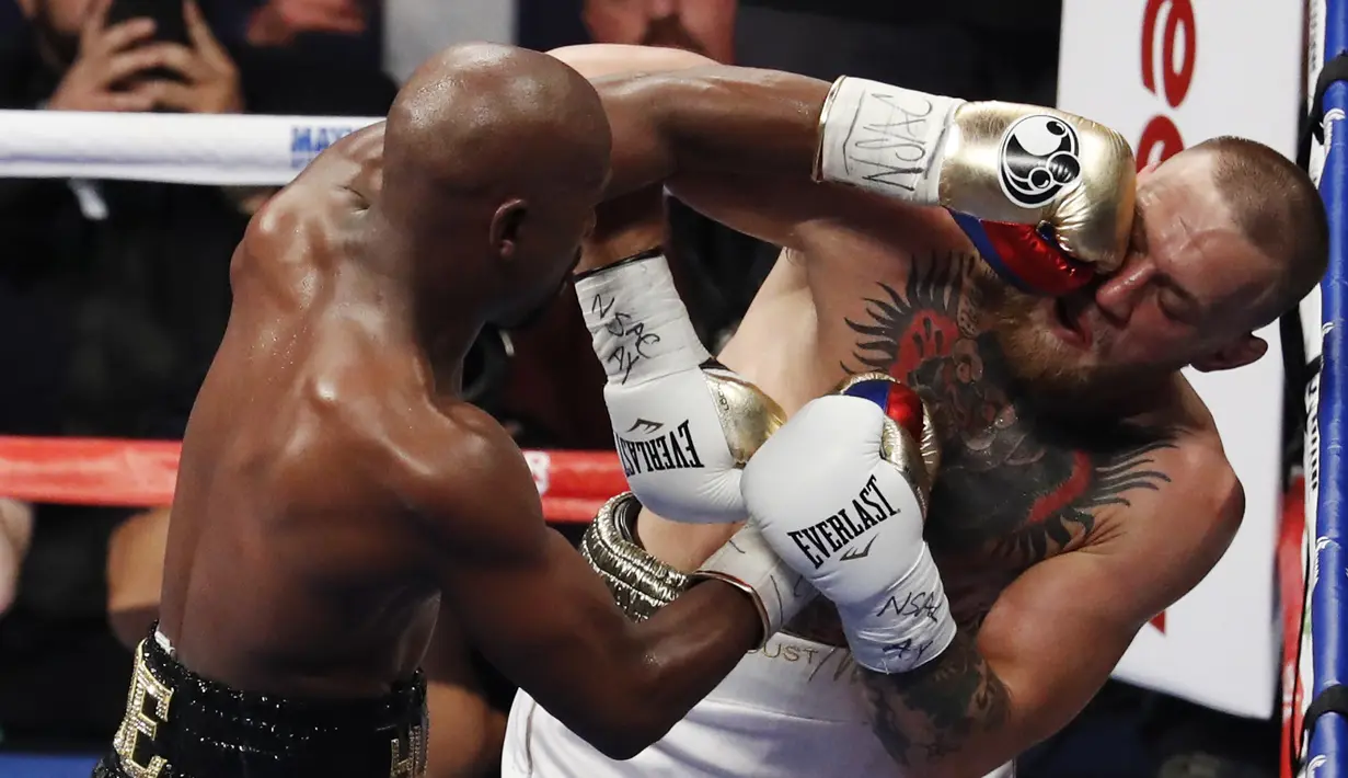 Floyd Mayweather Jr. melepaskan pukulan ke wajah Conor McGregor pada gelaran Tinju Dunia super welterweight boxing di MGM Arena, Las Vegas, (26/8/2017). Mayweather menang TKO atas McGregor. (AP/Eric Jamison)