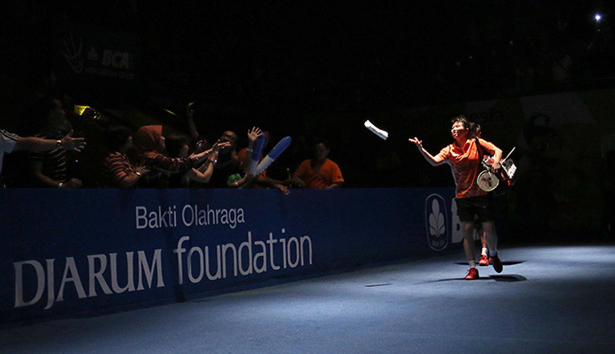 Tontowi Ahmad/Liliyana Natsir ganda campuran Indonesia melemparkan kaus ke arah penonton sebelum dimulainya semifinal BCA Indonesia Open Premier Super Series 2015 di Istora Senayan Jakarta, Sabtu (6/6). (Peksi Cahyo/Bola.com)