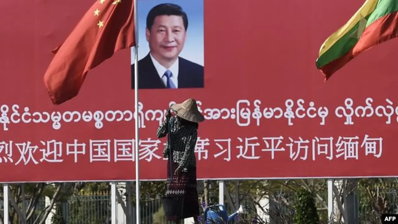 Seorang perempuan menyiram taman di depan papan ucapan selamat datang untuk Presiden China Xi Jinping, di Naypidaw, Myanmar, 17 Januari 2020.