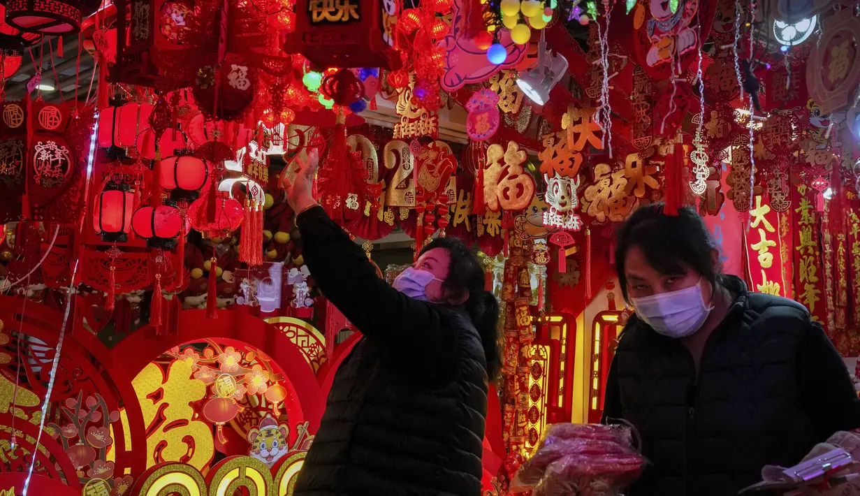 Seorang wanita memilih dekorasi Tahun Baru Imlek di sebuah mal di Beijing (16/1/2022). Beijing telah melaporkan infeksi omicron lokal pertamanya, beberapa minggu sebelum Olimpiade Musim Dingin akan dimulai. (AP Photo/Andy Wong)