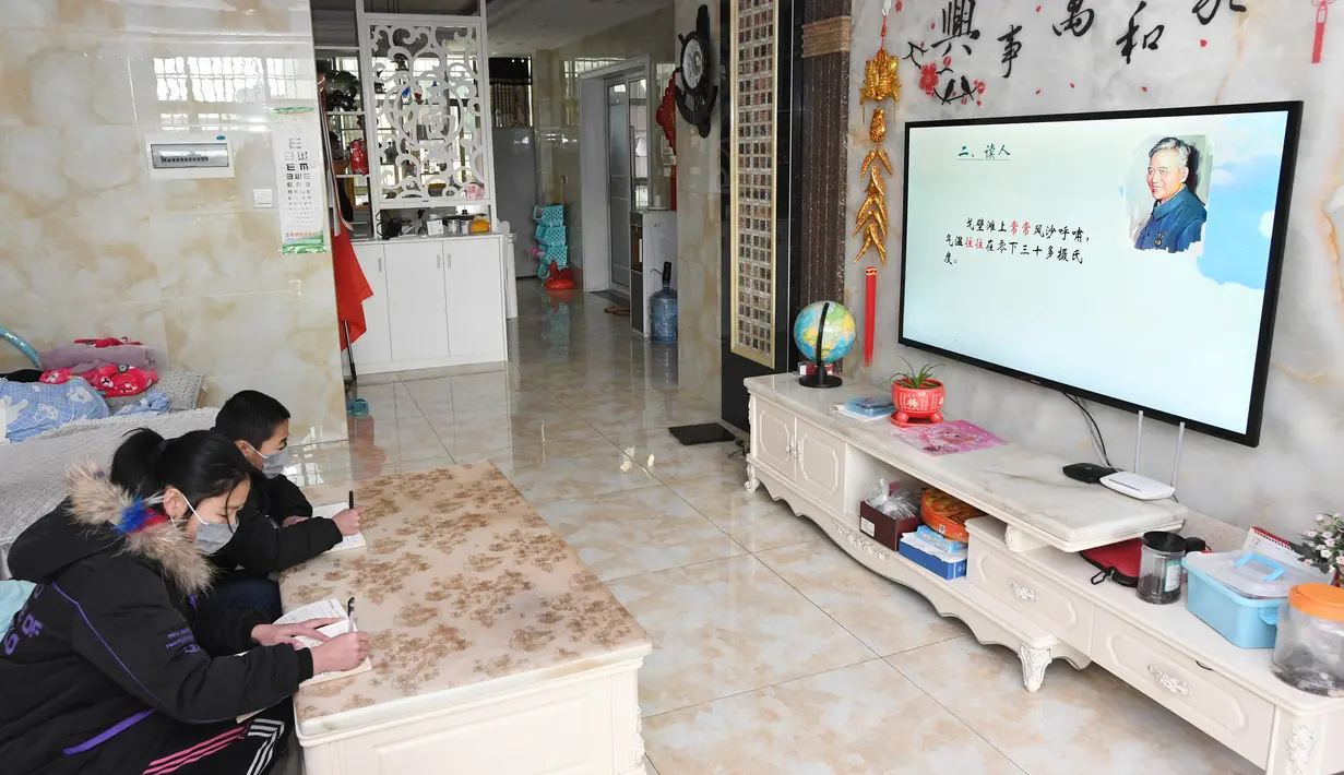 Anak kembar, Hu Jintao dan Hu Jinyan, belajar menggunakan TV jaringan di rumah mereka di Provinsi Jiangxi, 10 Februari 2020. Karena sekolah-sekolah di China diwajibkan menunda permulaan semester musim semi, para siswa di Provinsi Jiangxi belajar di rumah dengan berbagai cara. (Xinhua/Liu Jigang)