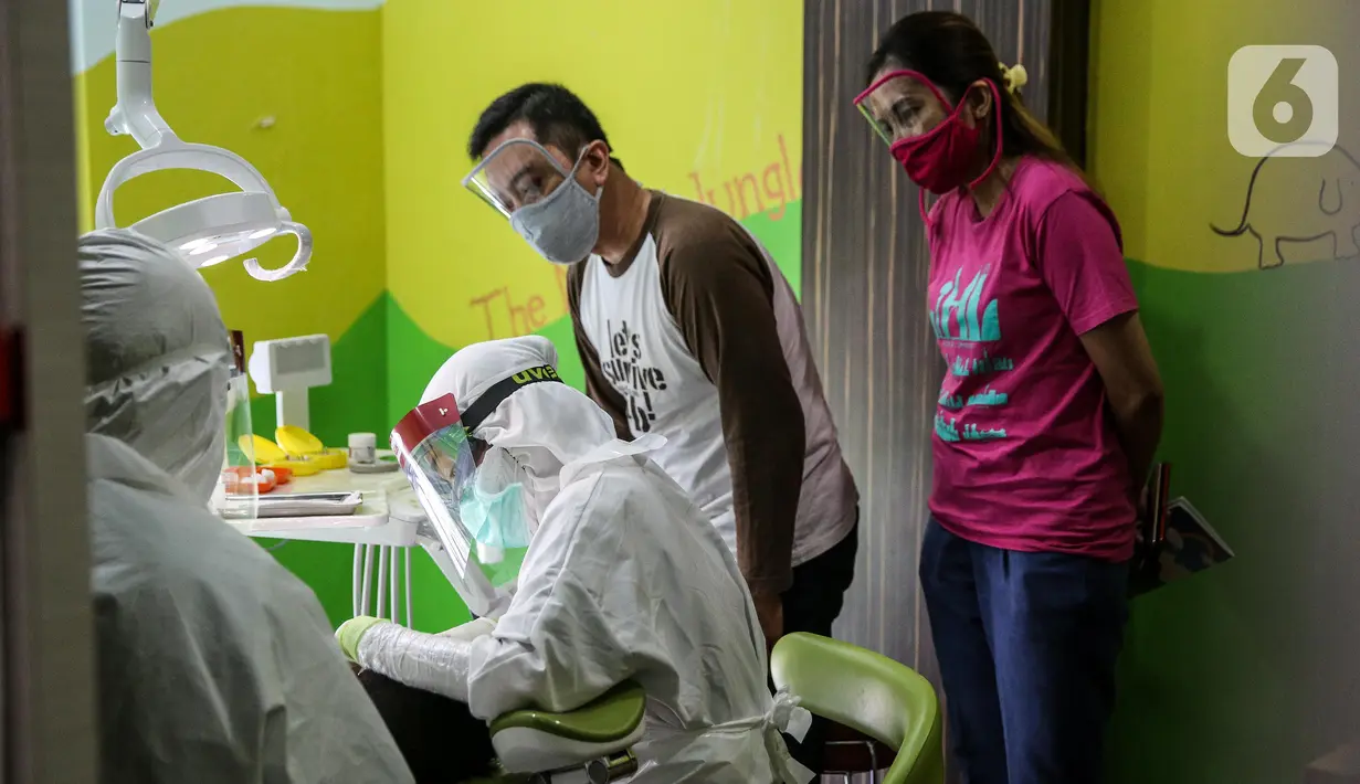 Dokter menggunakan APD memeriksa gigi pasien anak di klinik Medikids kawasan Kemang, Jakarta Selatan, Selasa (7/7/2020). Pelayanan dokter gigi dengan menggunakan APD lengkap  untuk memenuhi protokol kesehatan guna mencegah penyebaran covid-19 di era kenormalan baru. (Liputan6.com/Faizal Fanani)