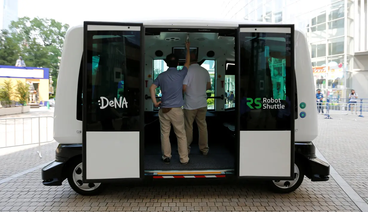 Dua orang lelaki mencoba menaiki Robot Shuttle saat didemonstrasikan di Tokyo, Jepang, Kamis (7/7). Dengan panjang hanya 4 meter, bus ini mampu menampung hingga 12 orang. (REUTERS / Toru Hanai)