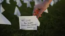 Zoe Nassimoff dari Argentina memegang bendera putih untuk mengenang orang AS yang meninggal karena COVID-19 dalam instalasi seni sementara seniman Suzanne Brennan Firstenberg 'Di Amerika: Ingat' di National Mall, Washington, AS, Jumat (17/9/2021). (AP Photo/Brynn Anderson)
