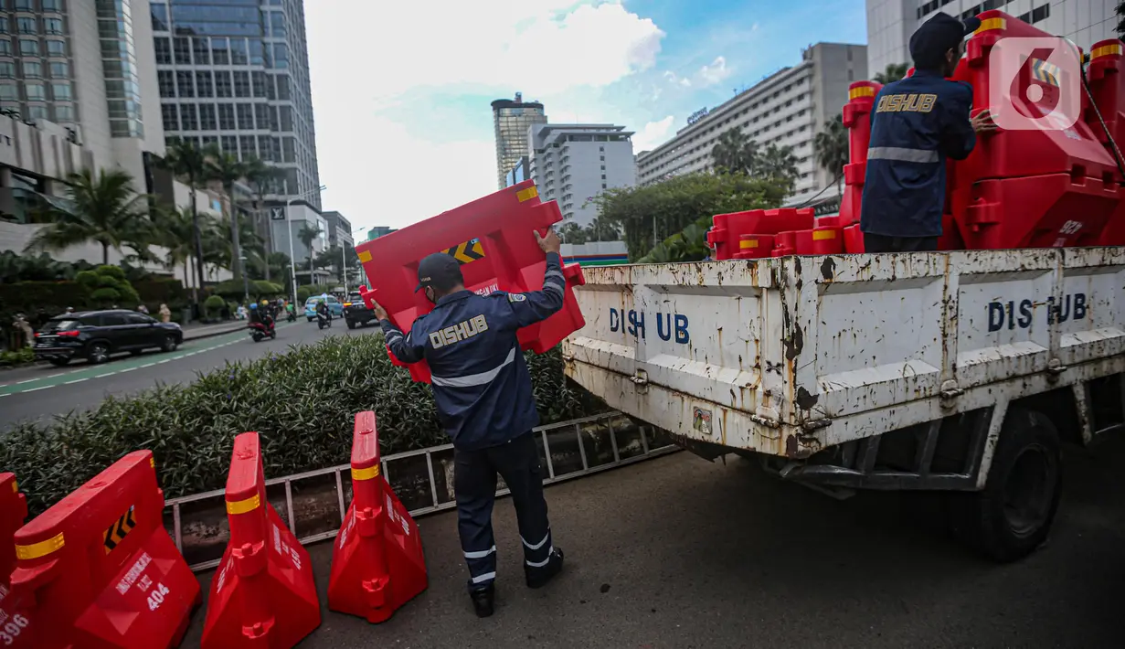 Petugas gabungan menurunkan pembatas jalan saat uji coba rekayasa lalu lintas di kawasan Bundaran HI, Jakarta Pusat, Senin sore (4/7/2022). Uji coba rekayasa lalu lintas dilaksanakan mulai hari ini, Senin 4 Juli hingga 10 Juli 2022 pukul 16.00-21.00 WIB. (Liputan6.com/Faizal Fanani)