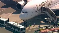 Petugas tanggap darurat berkumpul di luar pesawat setelah penumpang Emirates Airline dilaporkan jatuh sakit di Bandara Kennedy New York, Rabu (5/9). Sekitar 100 orang mengeluh sakit selama berada di pesawat dengan nomor penerbangan 521. (WABC 7 via AP)