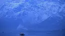 Orang-orang menikmati perjalanan dengan perahu dengan latar belakang pegunungan yang tertutup salju di danau Dal di Srinagar (11/1/2022). Danau Dal yang merupakan danau terbesar kedua di propinsi Jammu dan Kashmir negara bagian India ini merupakan pusat pariwisata dan rekreasi. (AFP/Tauseef Mustafa)