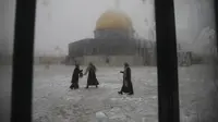 Para wanita bermain di salju dekat the Dome of the Rock atau Kubah Batu di kompleks Masjid Al Aqsa pada pagi bersalju di Kota Tua Yerusalem (18/2/2021). Pada 2013, badai salju besar terjadi di Yerusalem dan menyebabkan listrik mati di beberapa wilayah. (AP Photo/Mahmoud Illean)