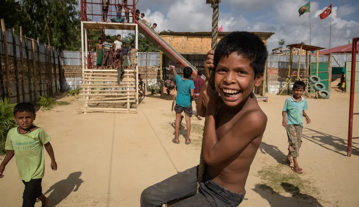 Anak-anak pengungsi Rohingya bergelantungan di tali saat bermain di taman bermain kamp pengungsi Thangkhali, dekat Cox's Bazar, Bangladesh, Kamis (9/8). (Ed JONES/AFP)