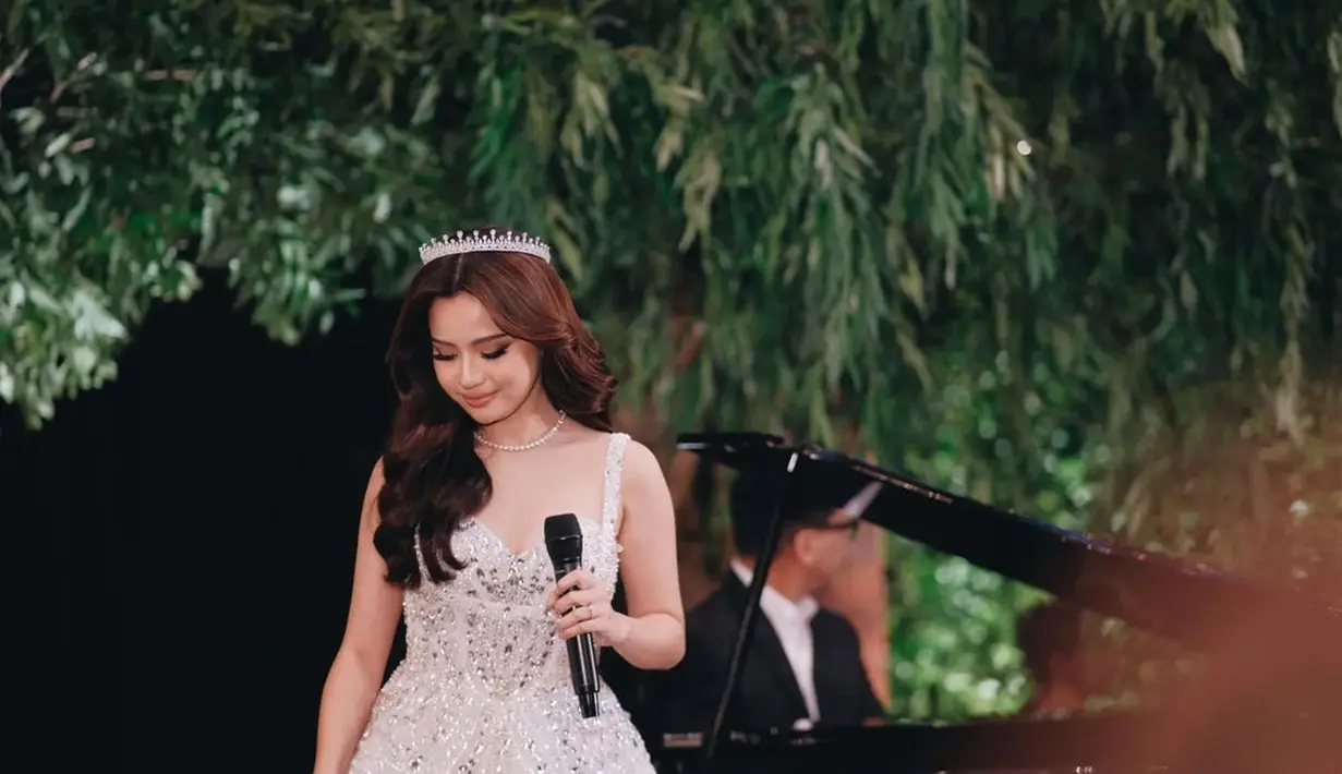 Gaun tersebut hadir dengan detail mutiara dan kristal, ditambah ekor panjang hingga menyapu lantai yang membuat keseluruhan tampilan Anggi menjadi glamor dan dramatis. [@rhay_david/@denivedder]