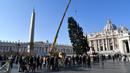 Sejumlah orang melihat alat berat yang dikerahkan untuk mendirikan pohon Natal raksasa di Alun-alun Santo Petrus, Vatikan, Kamis (23/11). Pohon Natal yang didatangkan dari Polandia ini tingginya mencapai 28 meter. (AP Photo/Andrew Medichini)