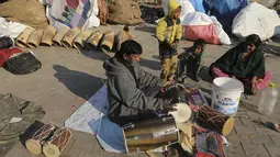 Seorang pria mencoba genderang  tradisional yang dibuatnya di daerah kumuh di Jammu, India (19/1/2021). Drum tradisional ini digunakan terutama saat pernikahan dan prosesi keagamaan. (AP Photo / Channi Anand)