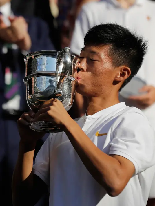 Petenis Taiwan Tseng Chun Hsin mencium trofi usai mengalahkan Jack Draper dari Inggris di final tunggal putra Kejuaraan Tenis Wimbledon Junior di London, (15/7). Petenis 16 tahun ini menang dengan skor 6-1, 6-7 (2/7), dan 6-4. (AP Photo/Ben Curtis)