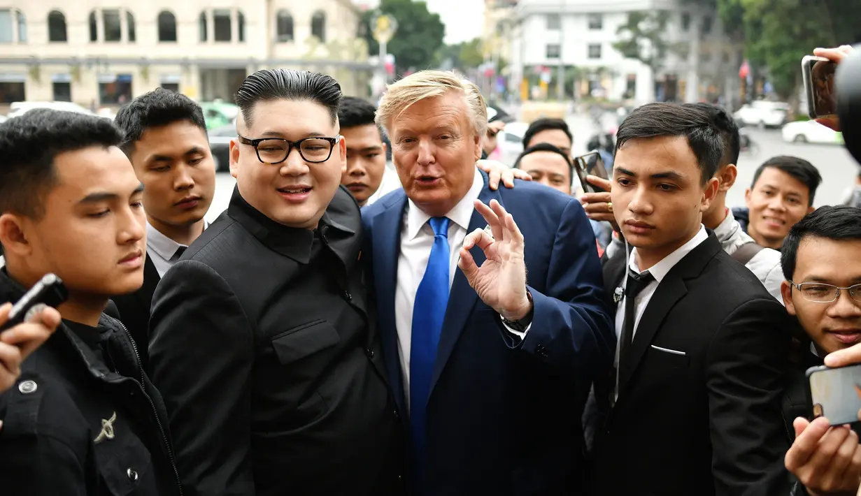 Peniru pemimpin Korut Kim Jong-un, Howard X dan peniru Presiden AS Donald Trump, Dennis Alan dikelilingi wartawan di luar Gedung Opera, Vietnam  (22/2). Aksi tersebut dilakukan menjelang KTT Trump-Kim mendatang di Hanoi. (AFP Photo/Manan Vatsyayana)