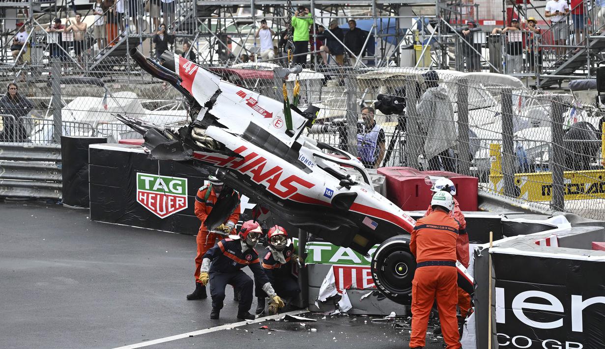 Sejumlah marshall berusaha mengevakuasi mobil pembalap Haas, Mick Schumacher usai mengalami kecelakaan saat Formula 1 GP Monako yang berlangsung di Circuit de Monaco, Minggu, 29 Mei 2022. (AP/Pool/Christian Bruna)