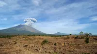 Gunung Agung mengeluarkan asap bercampur abu vulkanis terlihat dari desa Tulamben, Karangasem, Bali, Selasa (3/7). Walau terus mengalami letusan hampir sepekan terakhir, Gunung Agung masih berada pada status level III (siaga). (AFP/SONNY TUMBELAKA)