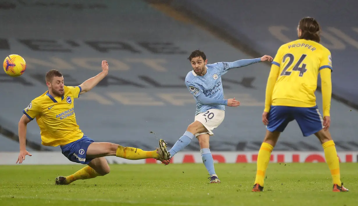 Gelandang Manchester City, Bernardo Silva (tengah) melepaskan tendangan ke gawang Brighton and Hove Albion dalam laga lanjutan Liga Inggris 2020/21 di Etihad Stadium, Rabu (13/1/2021). Manchester City menang 1-0 atas Brighton. (AFP/Martin Rickett/Pool)