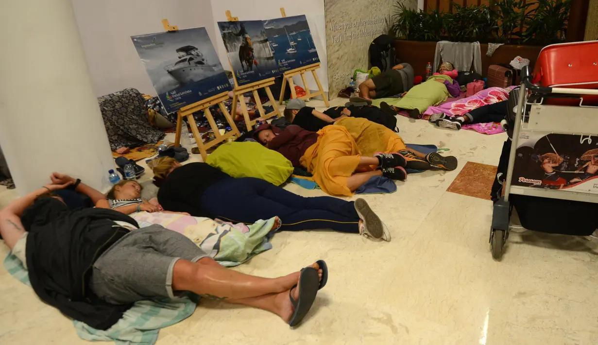 Wisatawan asing tidur di lantai saat menunggu jadwal keberangkatan pesawat di Bandara Internasional Praya Lombok, NTB, Senin (6/8). Imbas gempa 7 SR, para wisatawan terlantar di bandara karena jam pemberangkatan pesawat yang tertunda (AFP/SONNY TUMBELAKA)