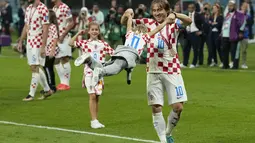 Kapten Kroasia Luka Modric mengayunkan putrinya Sofia untuk merayakan kemenangan timnya melawan Maroko pada pertandingan playoff perebutan peringkat ketiga Piala Dunia 2022 di Khalifa International Stadium di Doha, Qatar, Sabtu (17/12/2022). Modric telah 16 tahun membela Kroasia sejak debut di tim senior pada 2006 silam. (AP Photo/Francisco Seco)