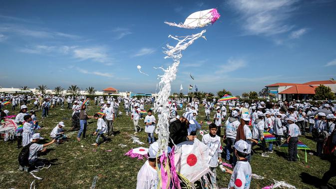 Anak-anak sekolah Palestina menerbangkan layangan dalam aksi solidaritas peringatan tujuh tahun gempa dan tsunami Jepang di Gaza, Selasa (13/3). Acara ini digagas oleh United Nations Relief and Works Agency (UNRWA). (SAID KHATIB/AFP)