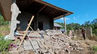 Seorang pria berdiri di dekat rumahnya yang rusak akibat gempa di Karangasem, Bali, Sabtu (16/10/2021). Gempa bumi dengan magnitudo 4,8 SR terjadi di darat pada jarak delapan kilometer barat laut Karangasem dengan kedalaman 10 km pada Sabtu  pukul 04.18 Wita. (AP Photo/Andi Husein)