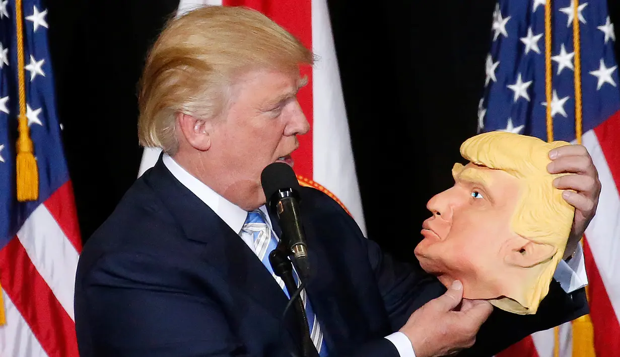 Capres dari Partai Republik Donald Trump melihat topeng wajah dirinya saat berkampanye di Sarasota, Florida, AS (7/11). Pilpres AS 2016 akan diadakan pada 8 November 2016 dan menjadi pilpres empat tahunan ke-58.  (REUTERS/Carlo Allegri) 