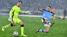 Penyerang Lazio, Ciro Immobile, berusaga merebut bola dari kiper Club Brugge, Simon Mignolet, pada laga Grup F Liga Champions di Olympic Stadium, Rabu (9/12/2020) dini hari WIB. Lazio bermain imbang 2-2 melawan Club Brugge. (AFP/Tiziana Fabi)