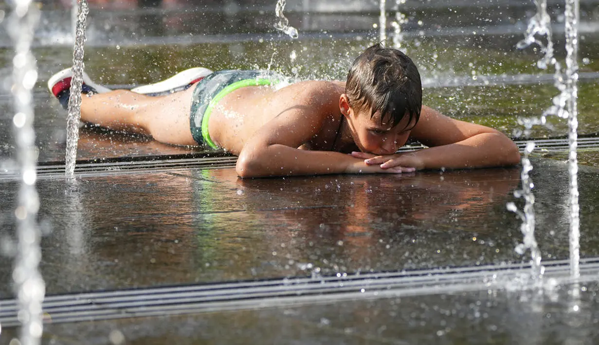 Seorang anak laki-laki menikmati cuaca panas sambil beristirahat di air mancur sebuah taman di sebelah tanggul Sungai Moskow, di Moskow, Rusia, Rabu (14/7/2021). Cuaca panas di Moskow berlanjut dengan suhu mencapai 34 derajat Celcius (93,2 Fahrenheit) dalam sehari. (AP Photo/Pavel Golovkin)
