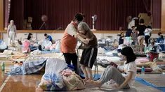 Pengungsi tua berusaha berdiri dari duduknya di lokasi pengungsian di Mabi, Prefektur Okayama, Jepang, Rabu (11/7). Pemerintah Jepang menyatakan banjir disertai tanah longsor telah menewaskan 179 orang. (Martin BUREAU/AFP)