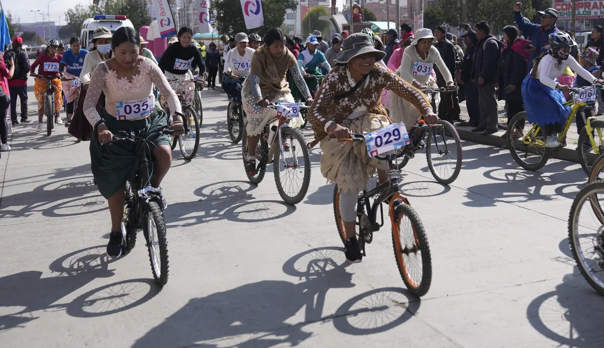 Dengan mengenakan rok panjang dan lebarnya, para pembalap wanita Bolivia ini tanpa kesulitan menggowes sepedanya. (AP Photo/Juan Karita)