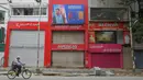 Seorang pria bersepeda di depan toko-toko yang tutup di area komersial saat pemberlakukan lockdown di Bangalore, Rabu (15/7/2020). Pusat IT India, Bangalore, kembali memberlakukan lockdown selama seminggu dimulai dari 14 Juli 2020 setelah adanya lonjakan kasus Covid-19. (Manjunath Kiran/AFP)