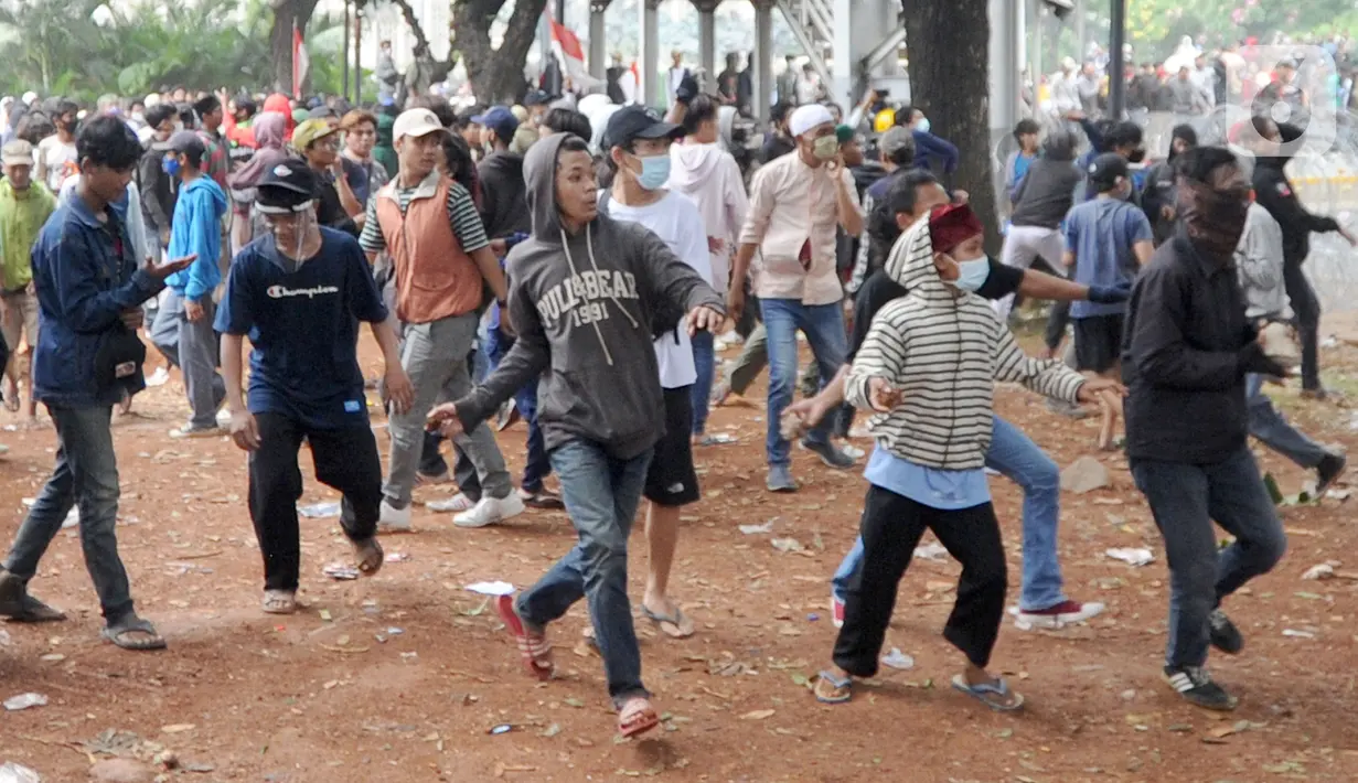 Sejumlah pengunjuk rasa melemparkan batu di Jalan MH Thamrin, Jakarta, Selas (13/10/2020). Massa pengunjuk rasa yang menolak Omnibus Law akhirnya dibubarkan dengan tembakan gas air mata. (merdeka.com/Arie Basuki)