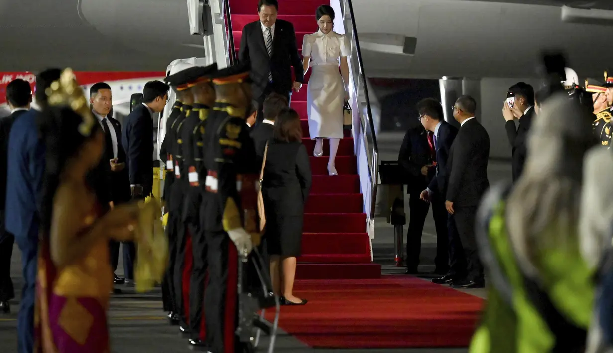 Presiden Korea Selatan Yoon Suk Yeol dan istrinya Kim Keon-hee tiba di Bandara Internasional Ngurah Rai di Bali, Minggu, 13 November 2022. Presiden Korea Selatan Yoon Suk Yeol tampil mengenakan jas berwarna hitam, sedangkan istrinya Kim Keon-hee berbusana serba putih. (Sonny Tumbelaka/Pool Photo via AP)