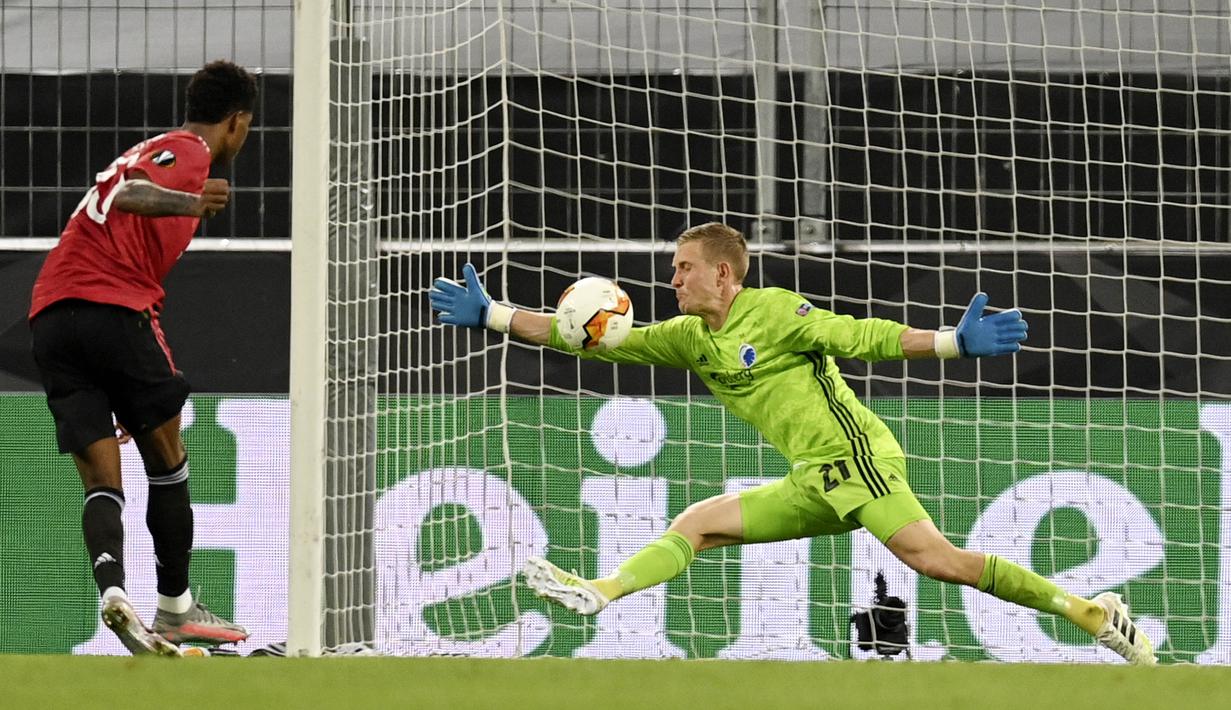 Kiper Copenhagen, Karl-Johan Johnsson, menghalau bola tendangan penyerang Manchester United, Marcus Rashford, pada laga Liga Europa di Stadion Rhein Energie, Senin (10/8/2020). MU menang tipis 1-0 atas Copenhagen. (Sascha Steinbach/Pool via AP)