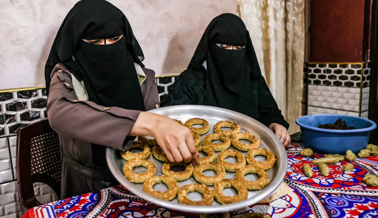 Kesibukan anggota keluarga Palestina menyiapkan kue-kue tradisional untuk dijual sebagai persiapan liburan Idul Fitri mendatang, di kota Rafah, Jalur Gaza, Selasa (4/5/2021). Pembuatan kue tradisional untuk Hari Raya Idul Fitri atau Lebaran yang menandai akhir bulan Ramadhan. (KATA KHATIB/AFP)