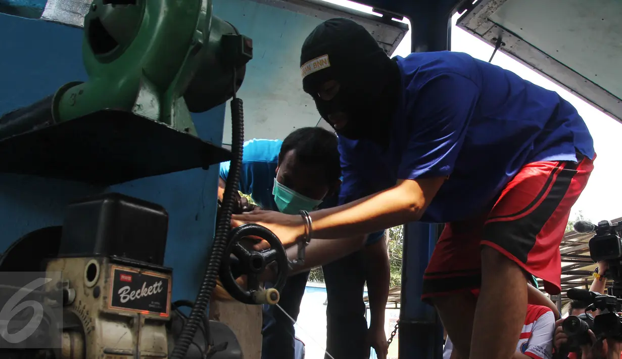 Seorang tersangka memasukan narkoba ke dalam mesin penghancur pada pemusnahan barang bukti tersebut di BNN, Jakarta, Rabu (17/6/2015). Sebanyak 18 kg sabu dan 622 butir ekstasi hasil pengungkapan BNN itu dimusnahkan. (Liputan6.com/Johan Tallo)