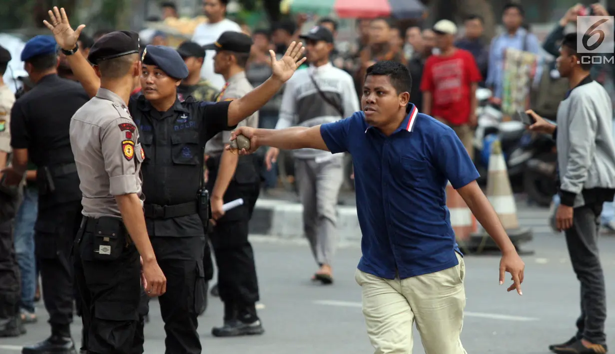 Massa membawa batu saat demonstrasi yang berujung ricuh di depan gedung KPK, Kuningan, Jakarta, Jumat (13/9/2019). Sempat terjadi baku hantam dalam demo itu saat massa aksi pendukung revisi Undang-Undang KPK mencoba merangsek untuk mencopot kain hitam yang menutupi logo KPK. (Liputan6.com/HO/Andri)