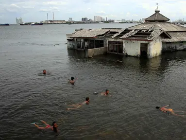 Sejumlah anak bermain di dekat Masjid yang terkena Abrasi di kawasan Muara Baru, Jakarta, Kamis (4/1). Sebagian anak-anak yang bermukim di kawasan tersebut banyak menghabiskan waktu saat berlibur sekolah untuk bermain di laut. (Liputan6.com/Johan Tallo)