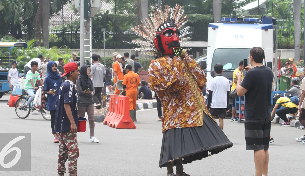 Warga memotret Ondel-ondel saat Car Free Day di Jakarta, Minggu (1/5). Meskipun bertepatan dengan peringatan Hari Buruh International tidak mempengaruhi masyarakat untuk menikmati CFD. (Liputan6.com/Angga Yuniar)
