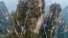 Dua kontestan berpakaian karakter Avatar berpacu sepanjang slackline di Pegunungan Huangshizhai di Zhangjiajie, Hunan, China, Minggu (23/12). Aksi tersebut dilakukan saat mengikuti slackline internasional.  (STR/AFP)